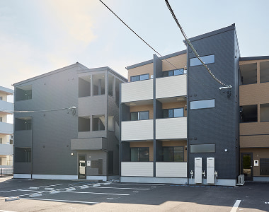 駅徒歩15分圏内の好立地にある広い駐車場を完備した、モノトーン調でモダンな外観デザインのアパート経営物件。