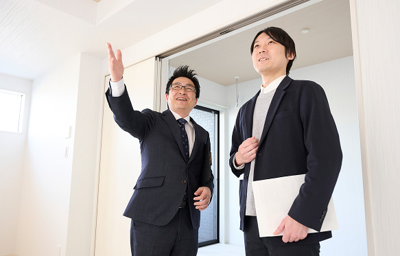 工務店の担当者が、注文住宅の土地探しについて、お客様に提案している様子です。